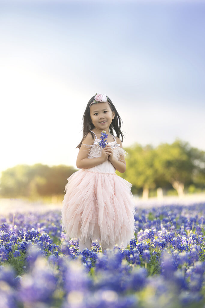 Young girl holds flowers in bluebonnet field