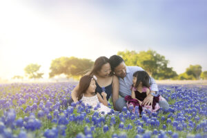 Family laughs with toddler in bluebonnet field