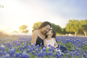 mother and daughter snuggle in flower field