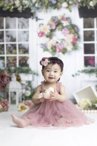 8 month old girls holds flowers on a spring photography set