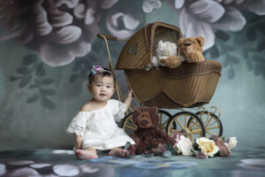 Baby girl sits near pram during photo session