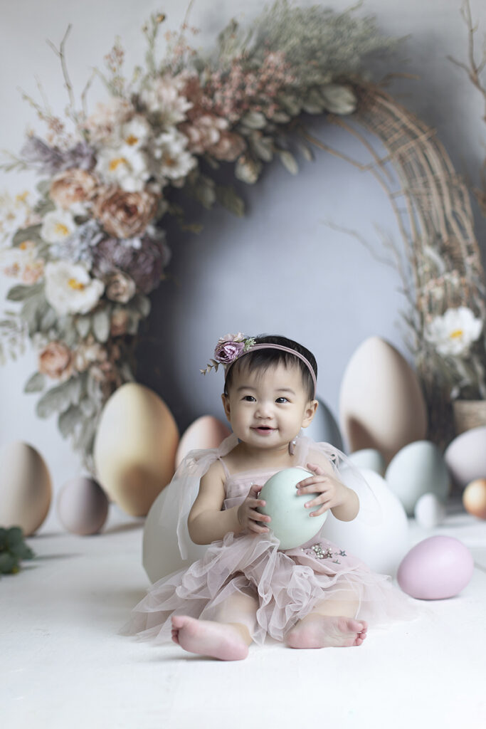 8 month old holds decorative egg