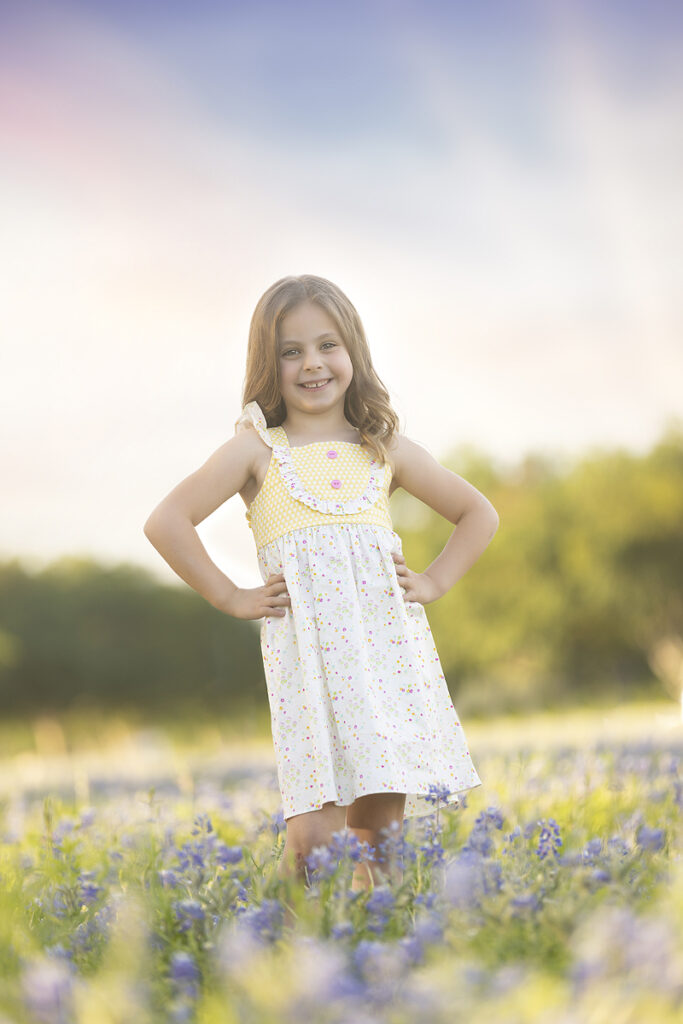 Young girl smiles while standing in bluebonnets