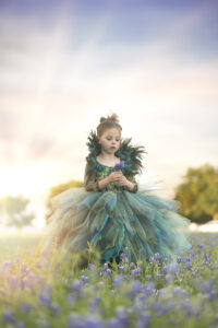 Young girl in couture gown holds flowers in field