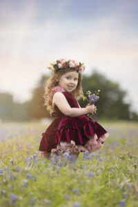 Toddler girl collects wildflowers at bluebonnet photography session