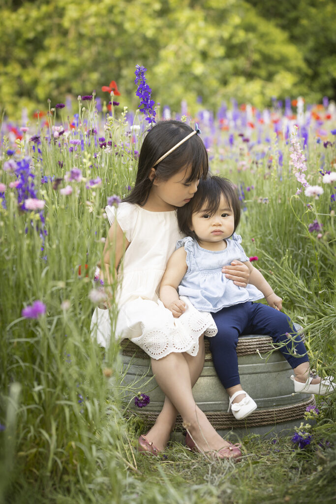 Sisters embrace sitting in flower field
