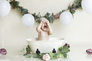 Baby laughs in tub at cake smash photo session