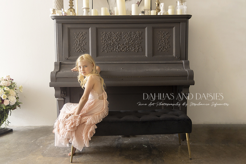 Girl sits at vintage piano during photoshoot