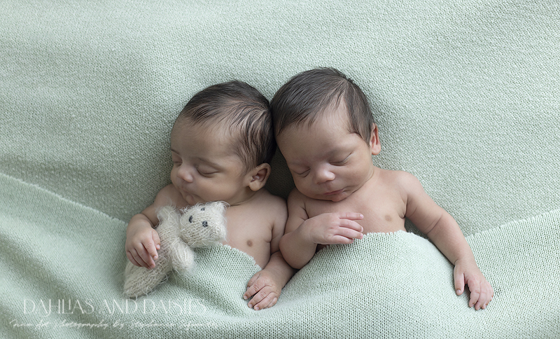 Twin newborn boy lay on green fabric