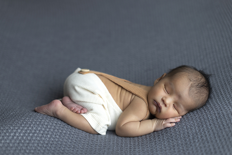 Newborn boy on grey fabric