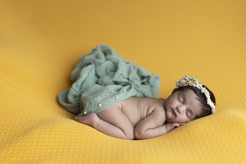 newborn girl on yellow fabric