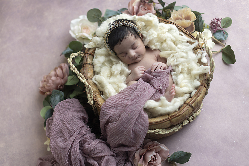 Newborn girl lays in floral basket