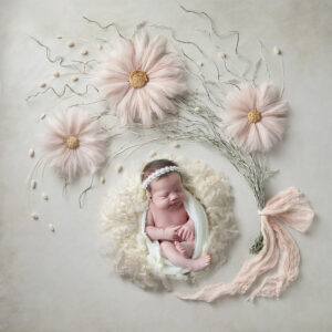 Newborn girl sleeps among flowers