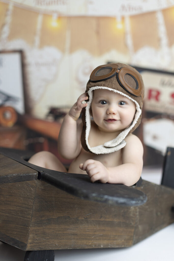 Boy smiles at camera while sitting in wooden baby plane