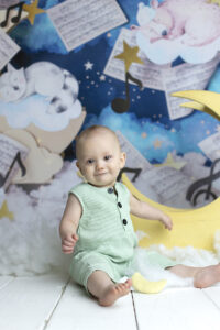 6 month old boy sits with yellow wooden moon