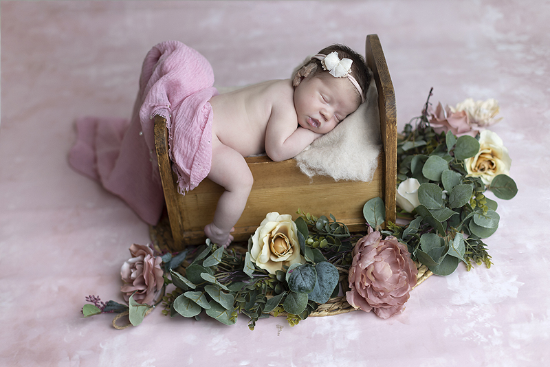 Dallas newborn girl sleep on raised baby bed on pink backdrop