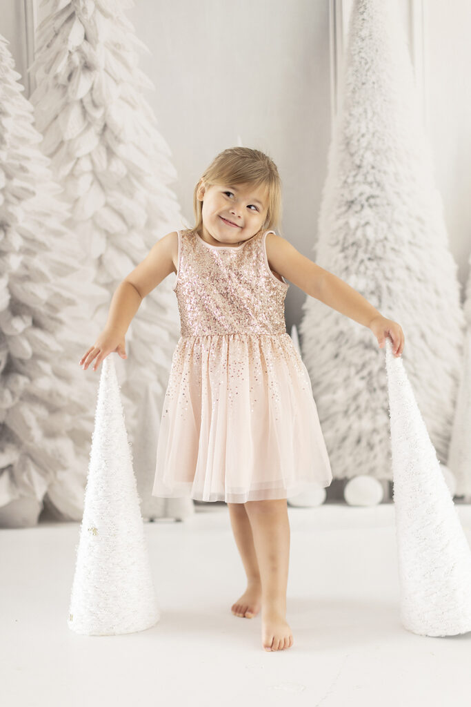 Young girl poses against white snow tree backdrop