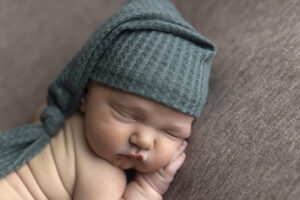Newborn boy wearing green sleep hat