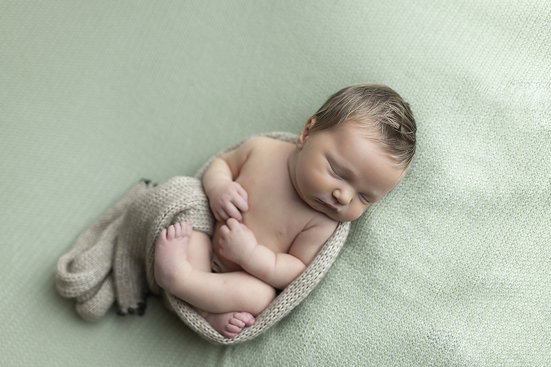 Newborn boy sleep on back on green fabric