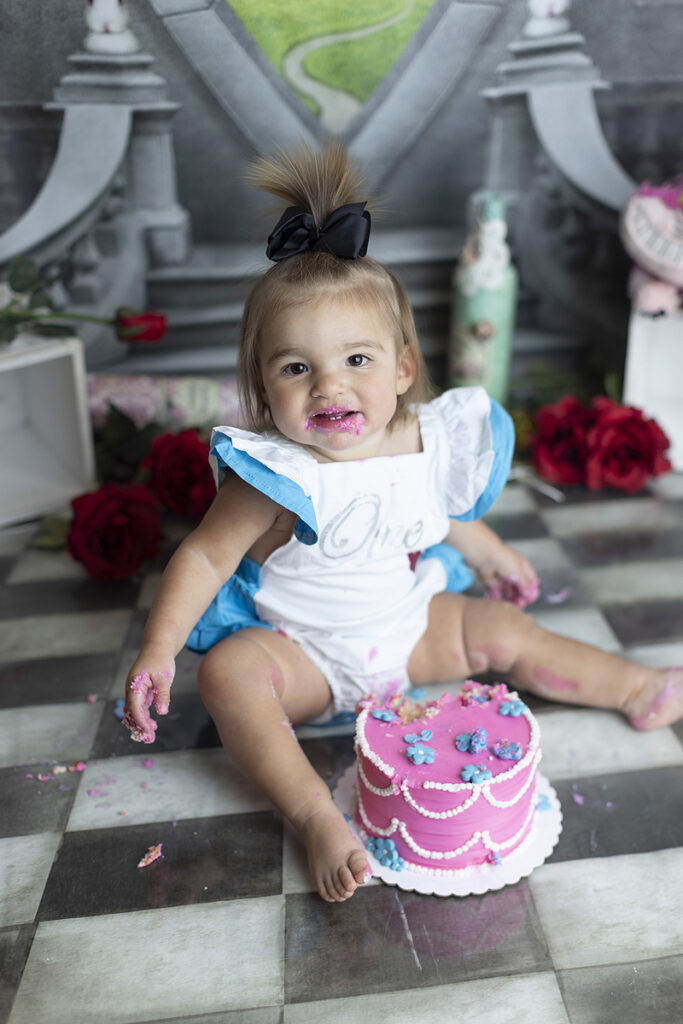 1 year old eats cake at her Alice in Wonderland cake smash