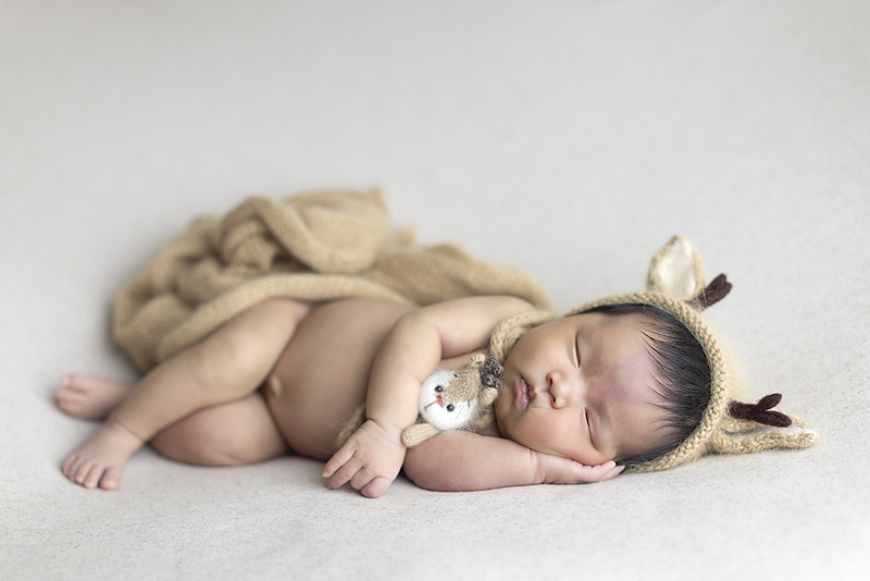 Newborn girls lay don side snuggle tiny reindeer stuffy
