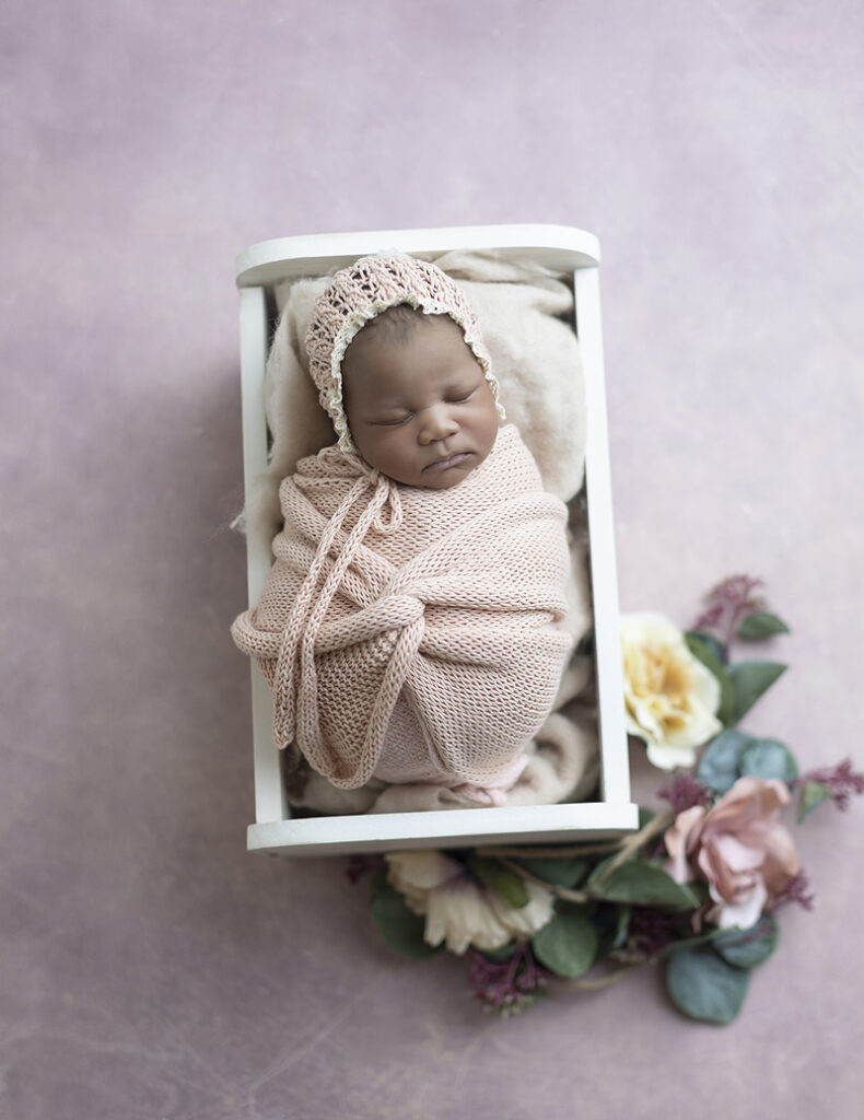 Newborn girls rests swaddled in tiny bed