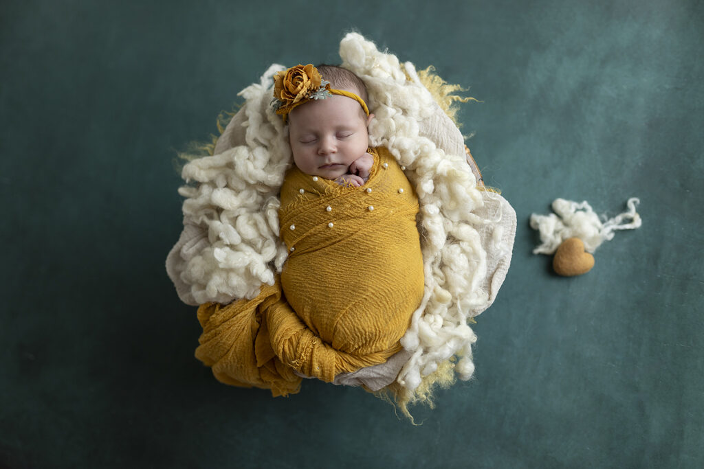 newborn girl swaddled in mustard yellow