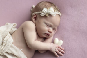 Newborn girl holds heart
