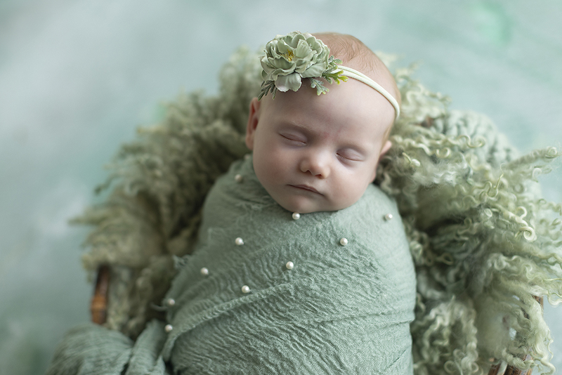 Newborn girl wrapped in mint green
