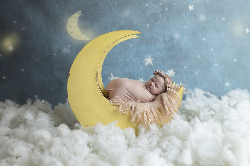 Newborn girl sleeps on moon