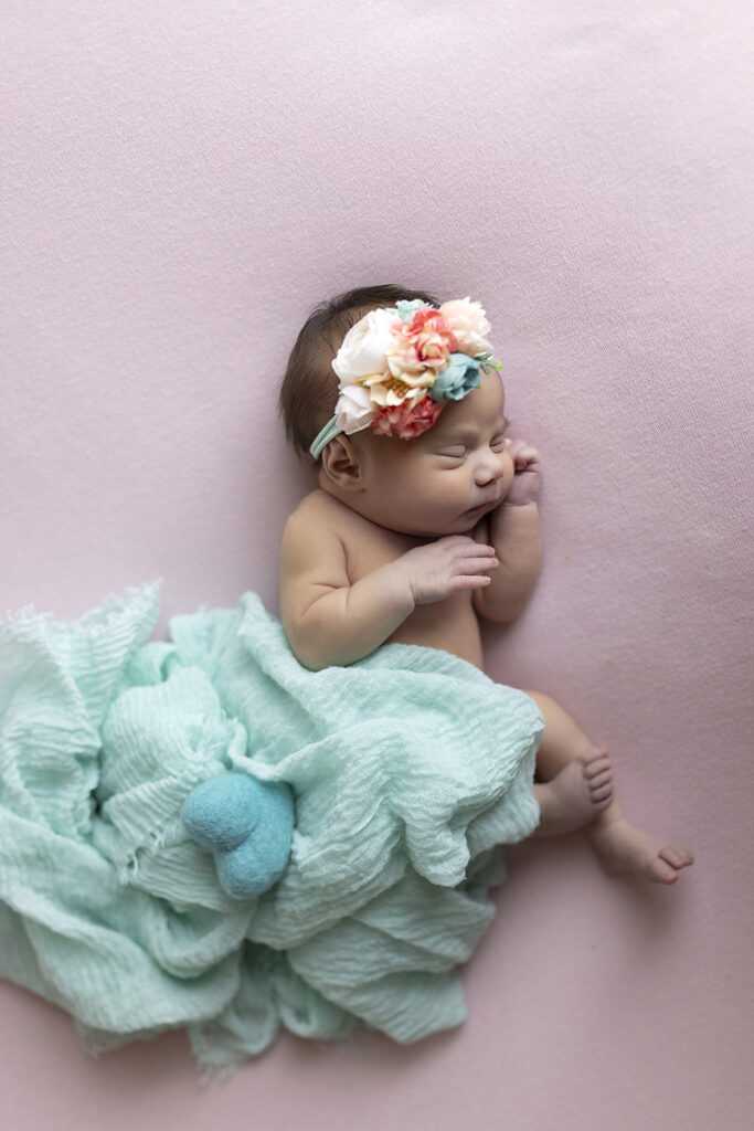 newborn lays on pink fabric