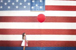 Girl stands in front of an American flag murel