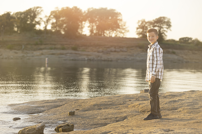 Boy stands near lake at Dallas family photographer session