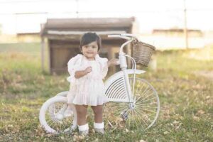 Baby girl stands with white bike at Dallas photo session